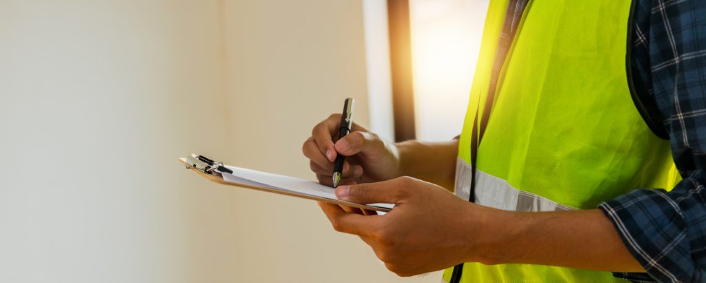 An inspector wear safety vest and checking list into clipboard.